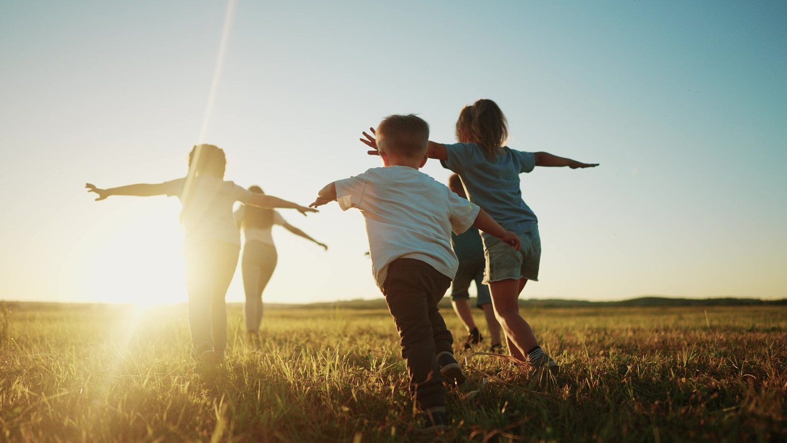 Kids run in the park at sunset.